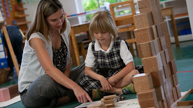 teacher and Primary school student looking at Montessori Curriculum