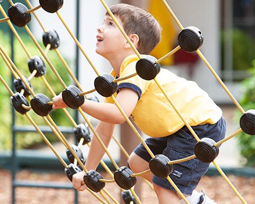 boy climbing outside at montessori elementary school